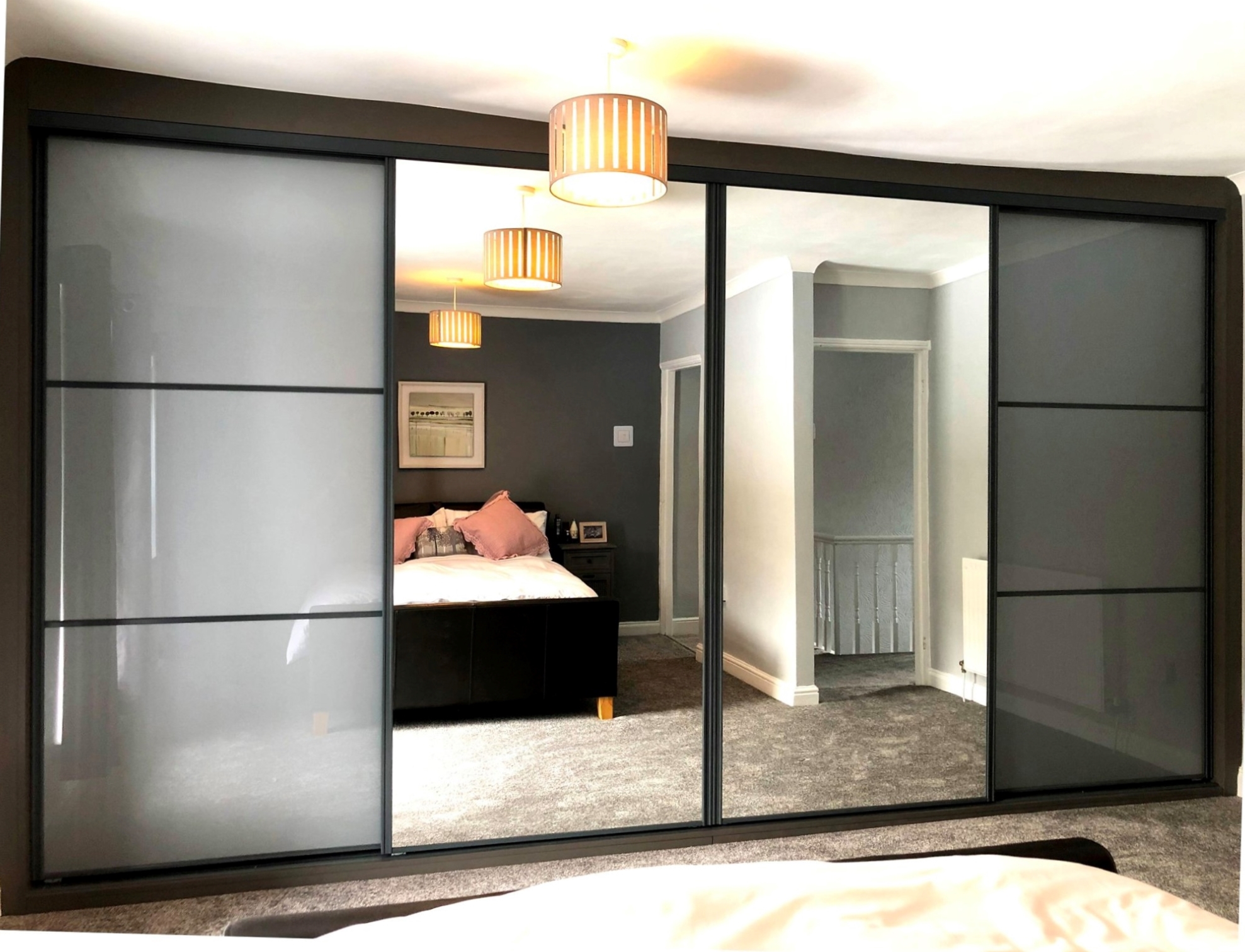 Frosted white-grey coloured glass sliding doors with horizontal strips either side of a full-height central mirror, in a dark wood surround in Abertillery