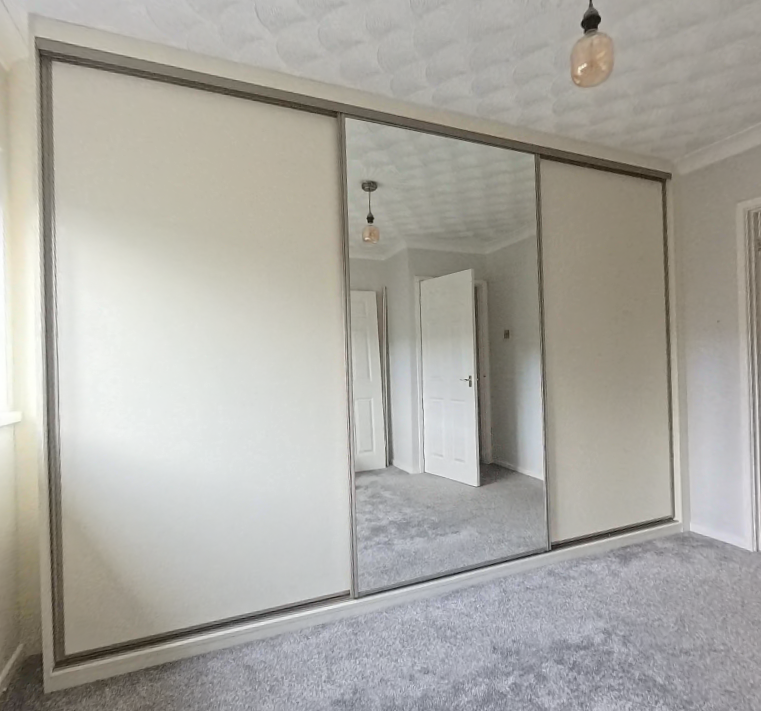 White panel sliding doors with a full-height central mirror and silver frames in Port Talbot