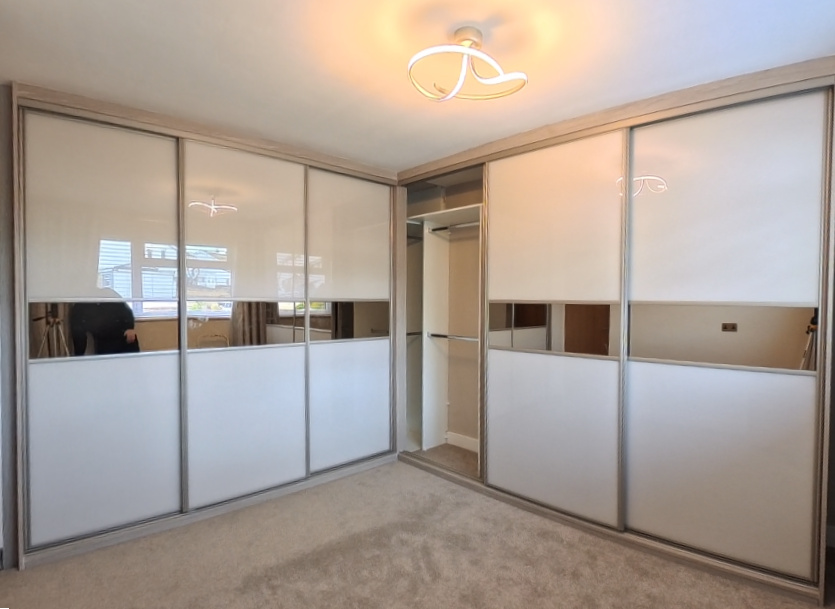 Corner run of sliding doors with cream panels, oak-effect frames and mirror bands in Newport