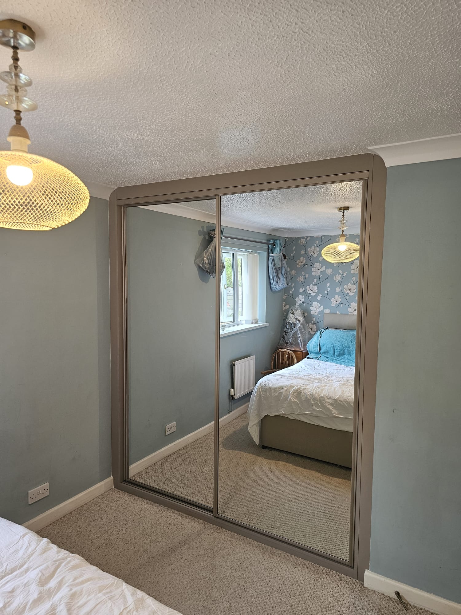 The same pale blue bedroom fitted with taupe-framed full mirror sliding wardrobe doors