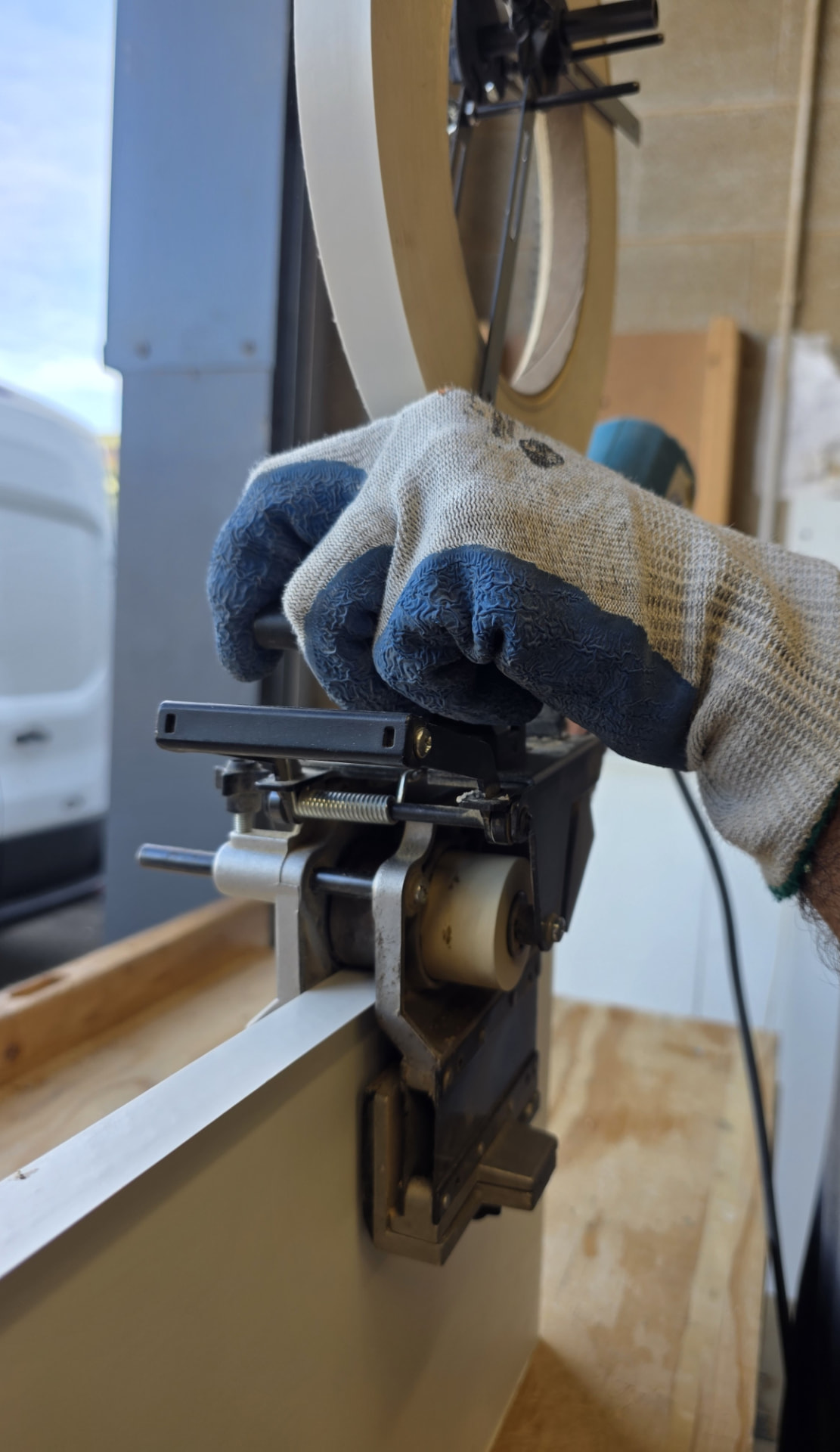An edge banding machine applying edging tape to a sliding wardrobe door panel in the Pontypridd workshop